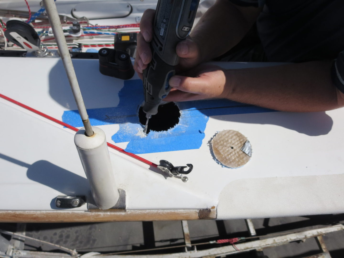 A person using a drill to make holes in the side of a boat.