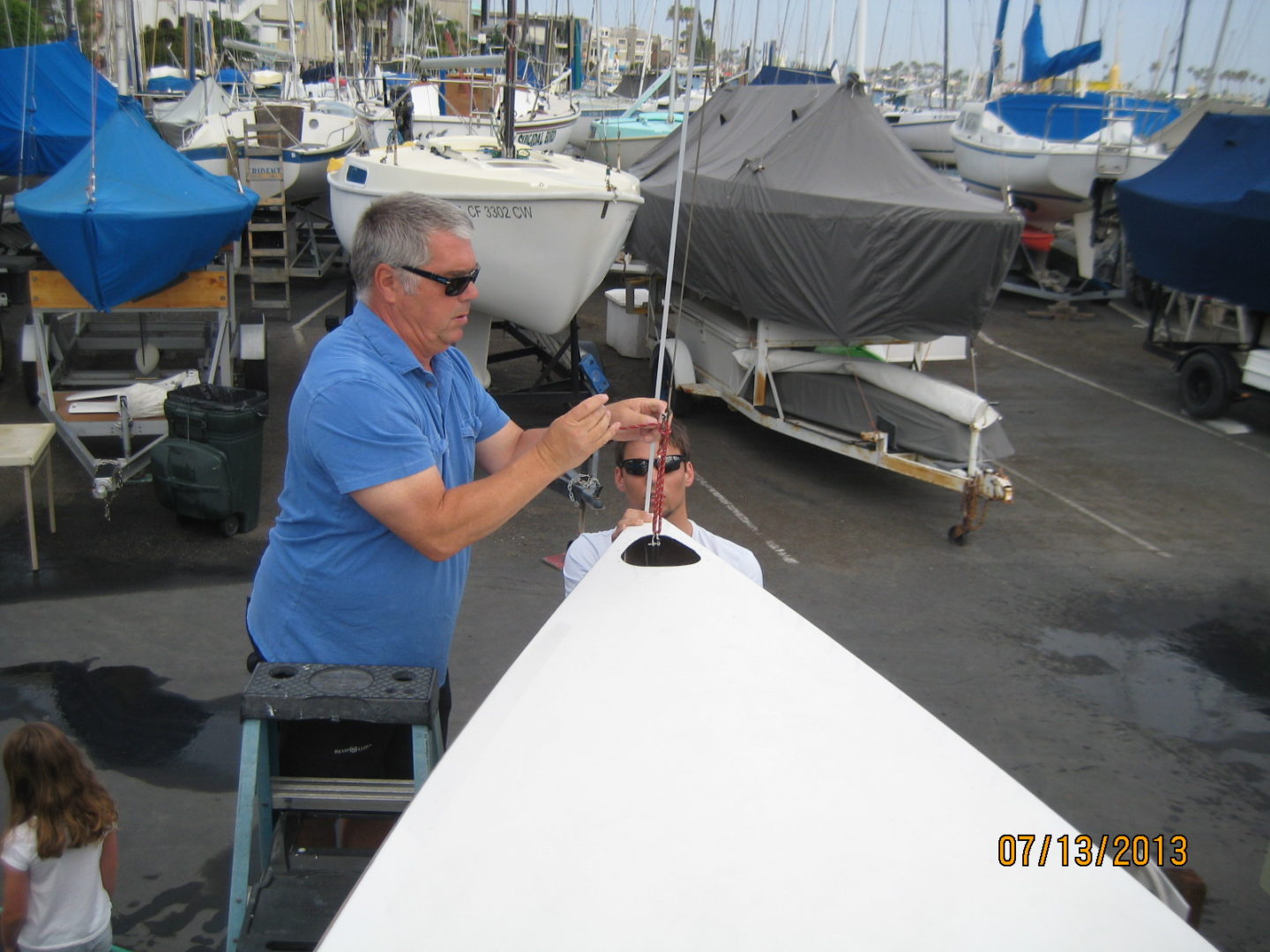 A man is working on the sail of his boat.