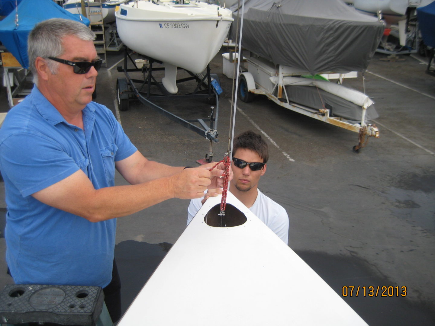 A man and a boat owner working on the sail.