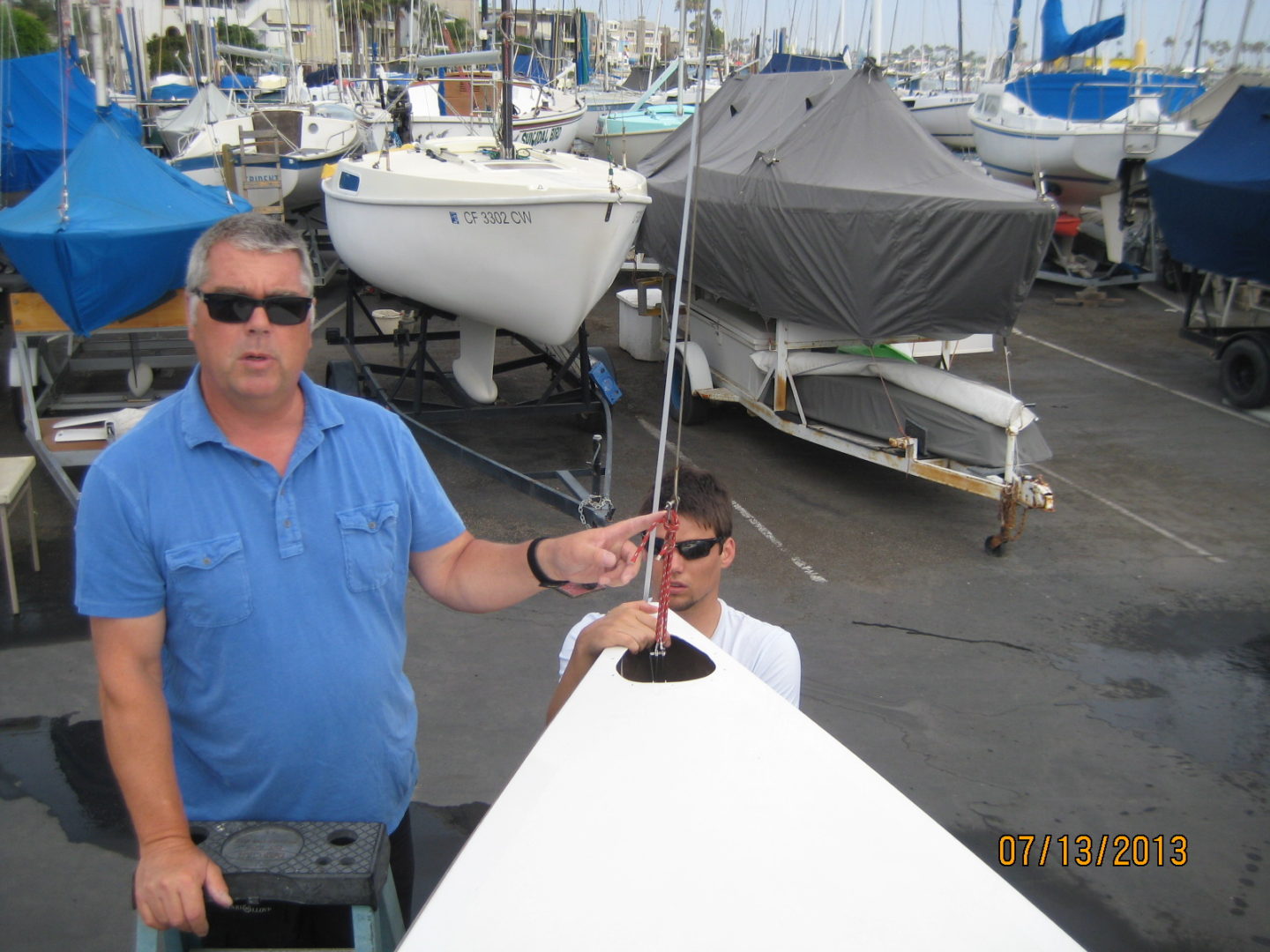 Two men standing next to a boat in the water.