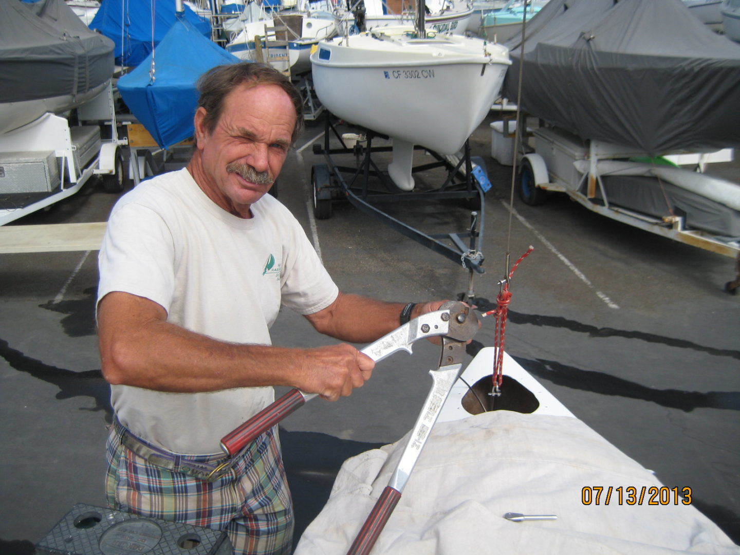 A man in plaid pants and white shirt holding a boat.