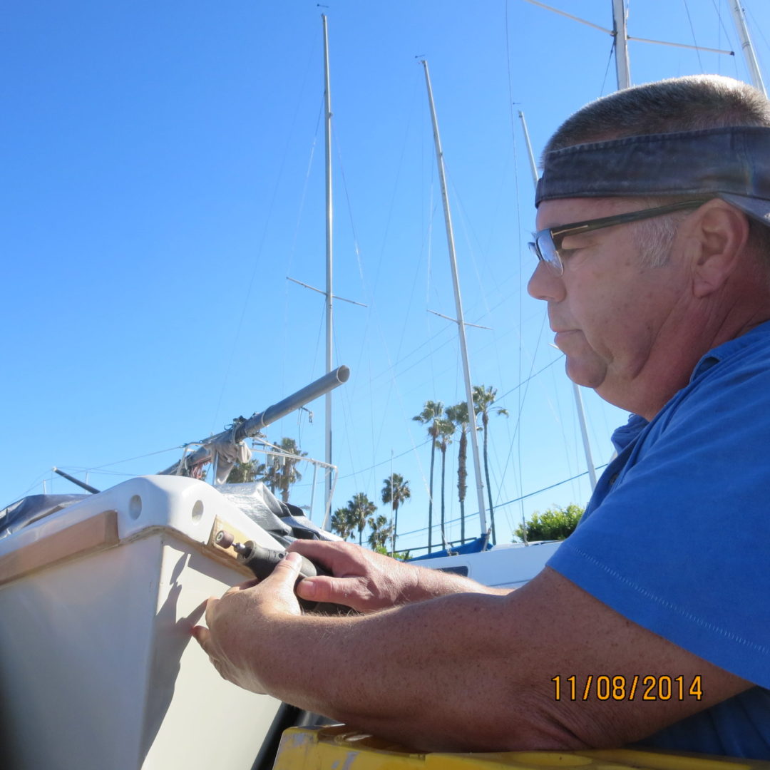 A man is working on the side of a boat.