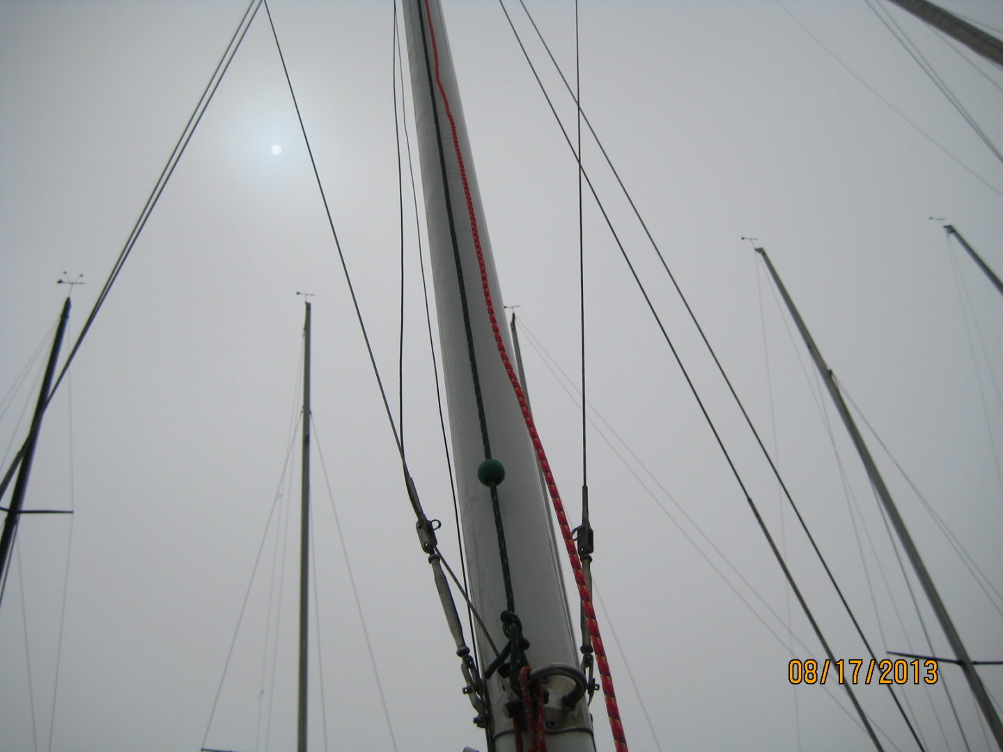 A sail boat is in the water under some wires.