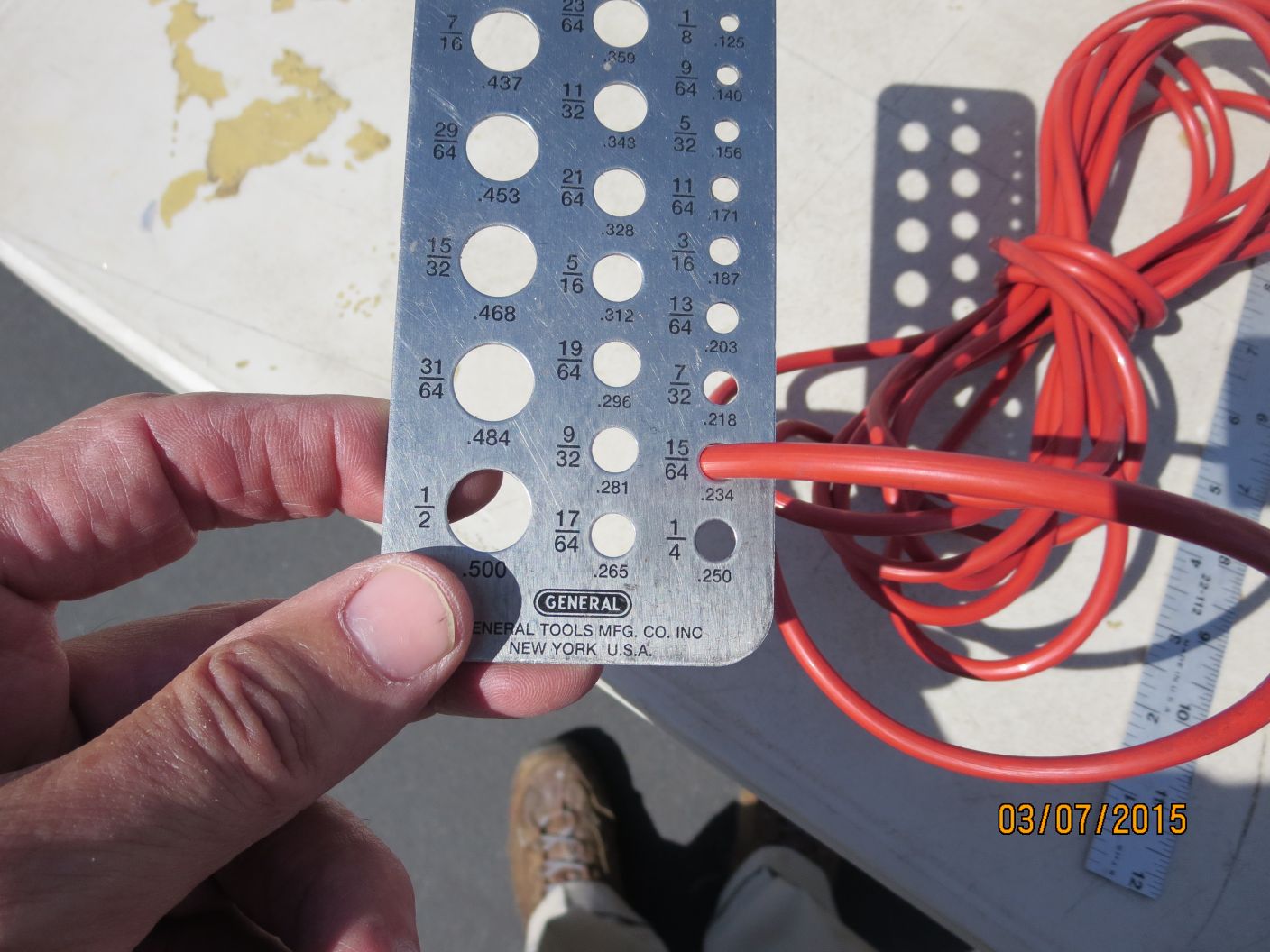 A person holding up a metal device with wires in the background.