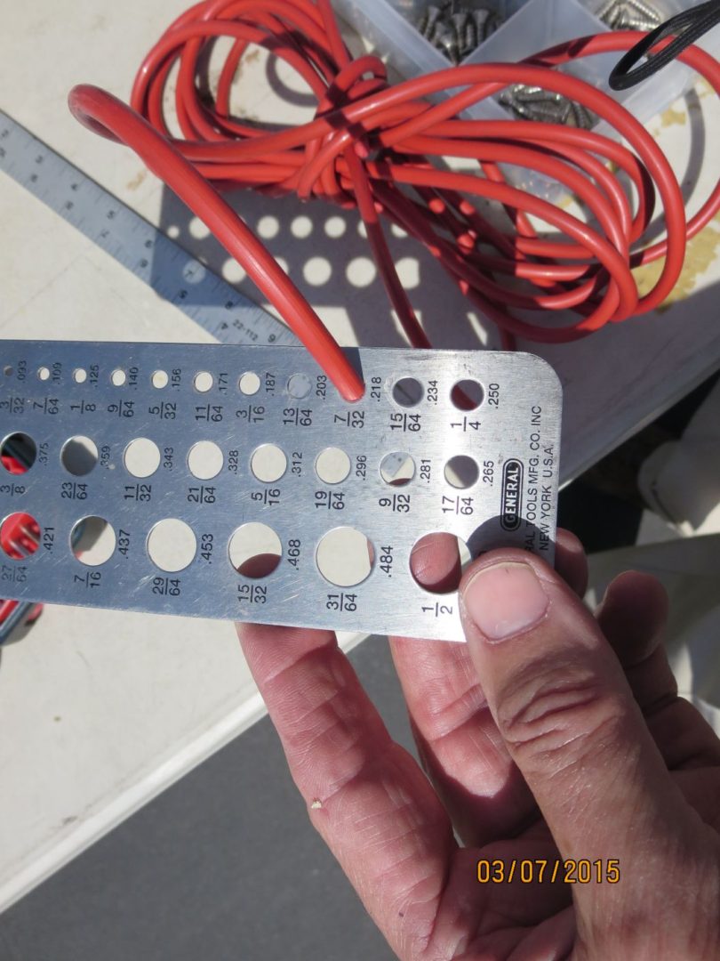 A person holding up a metal ruler with holes in it.