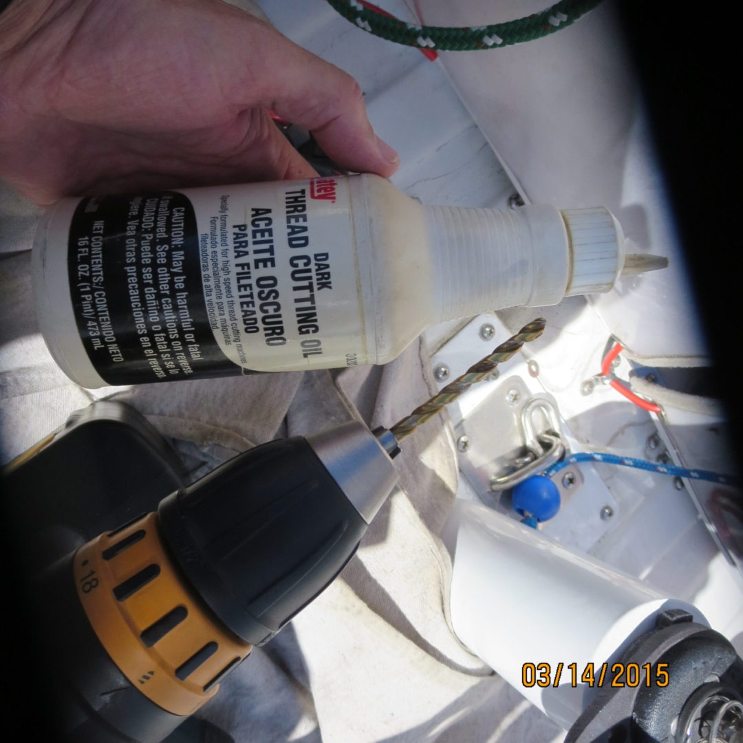 A person holding a bottle of glue next to a drill.