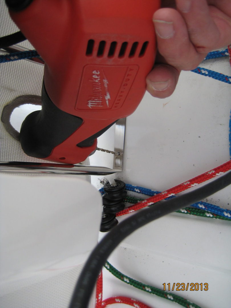 A person using an electric drill to cut the cable.