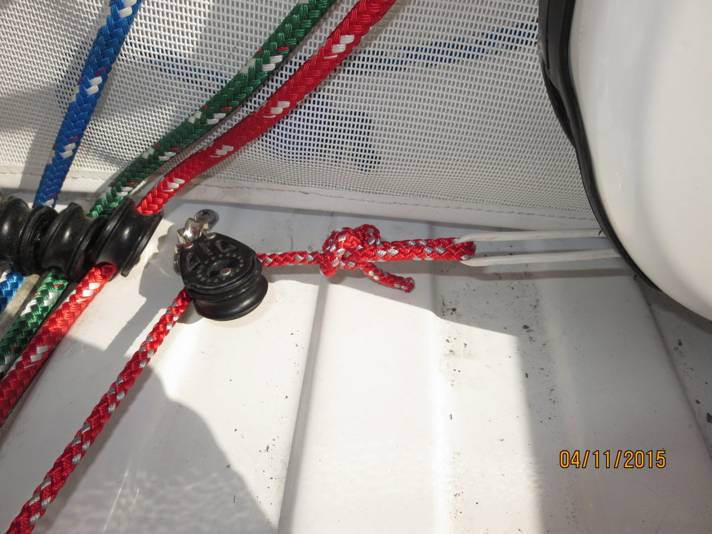 A red, white and blue rope hanging on the side of a boat.