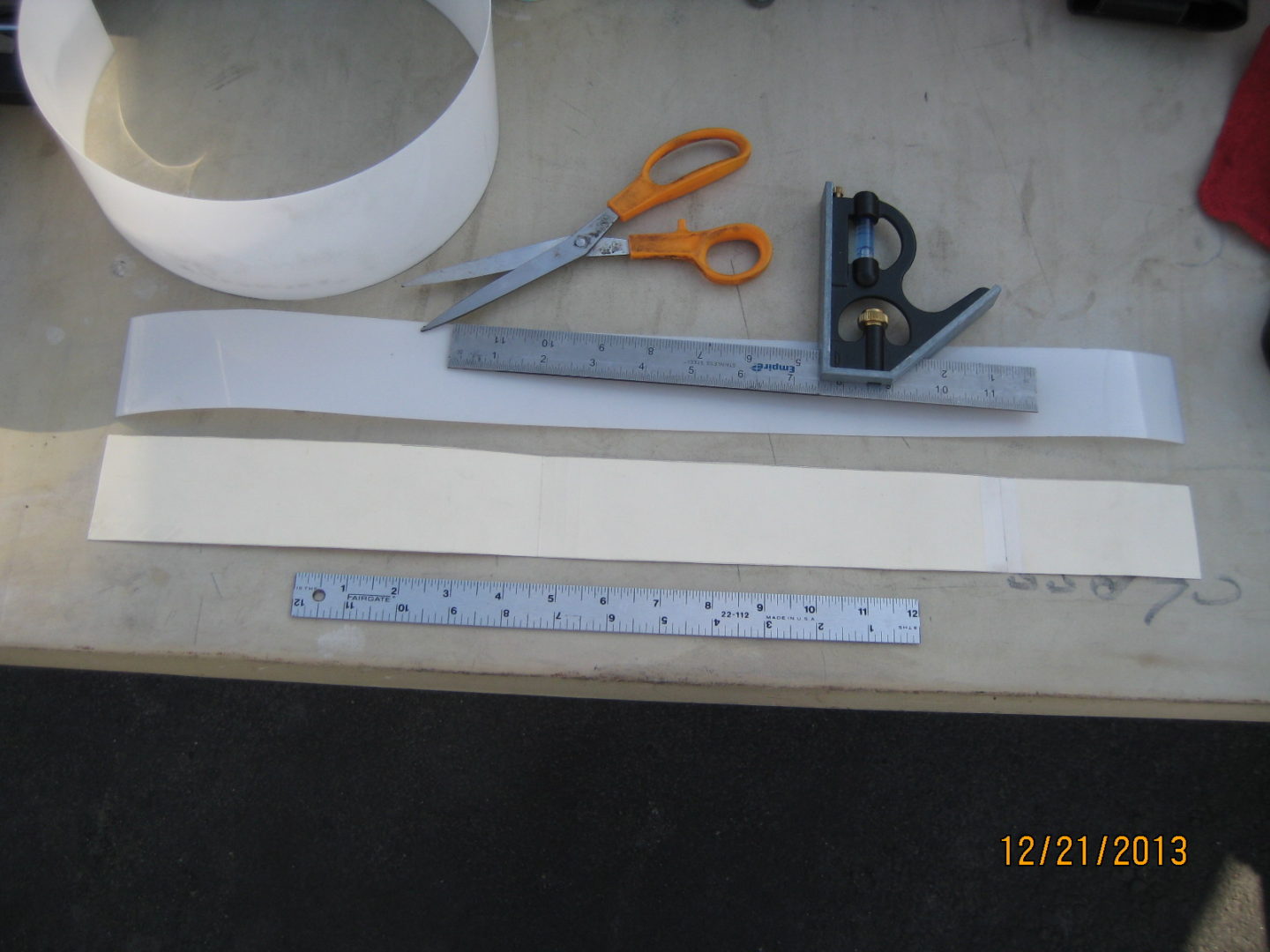 A pair of scissors, ruler and tape measure on top of a table.