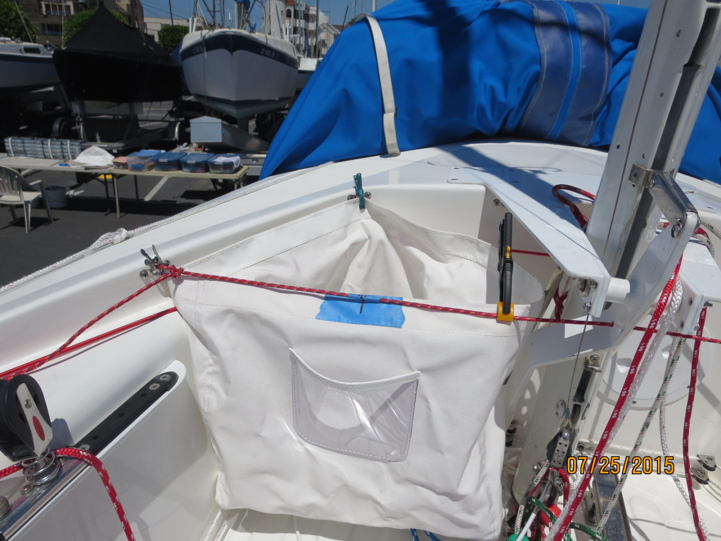 A white sail boat with blue tarp on the side.