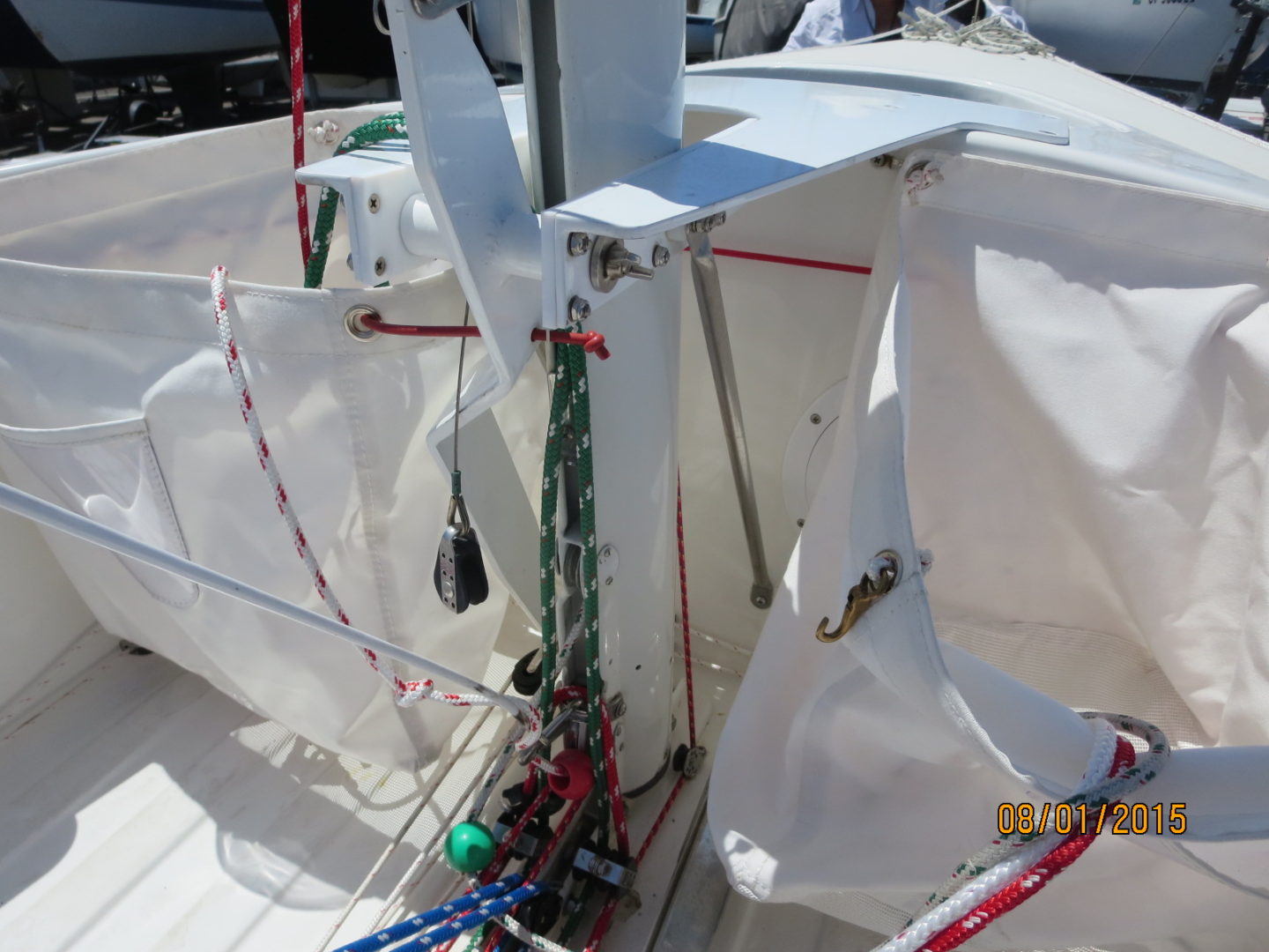 A boat with ropes and a white sail on the deck.