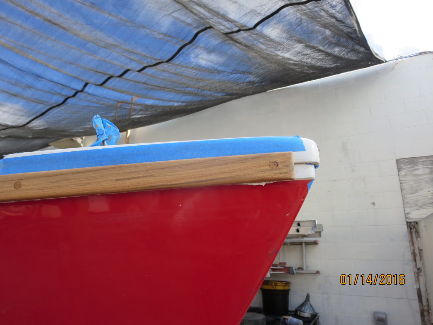 A red boat with blue hull in the middle of a garage.