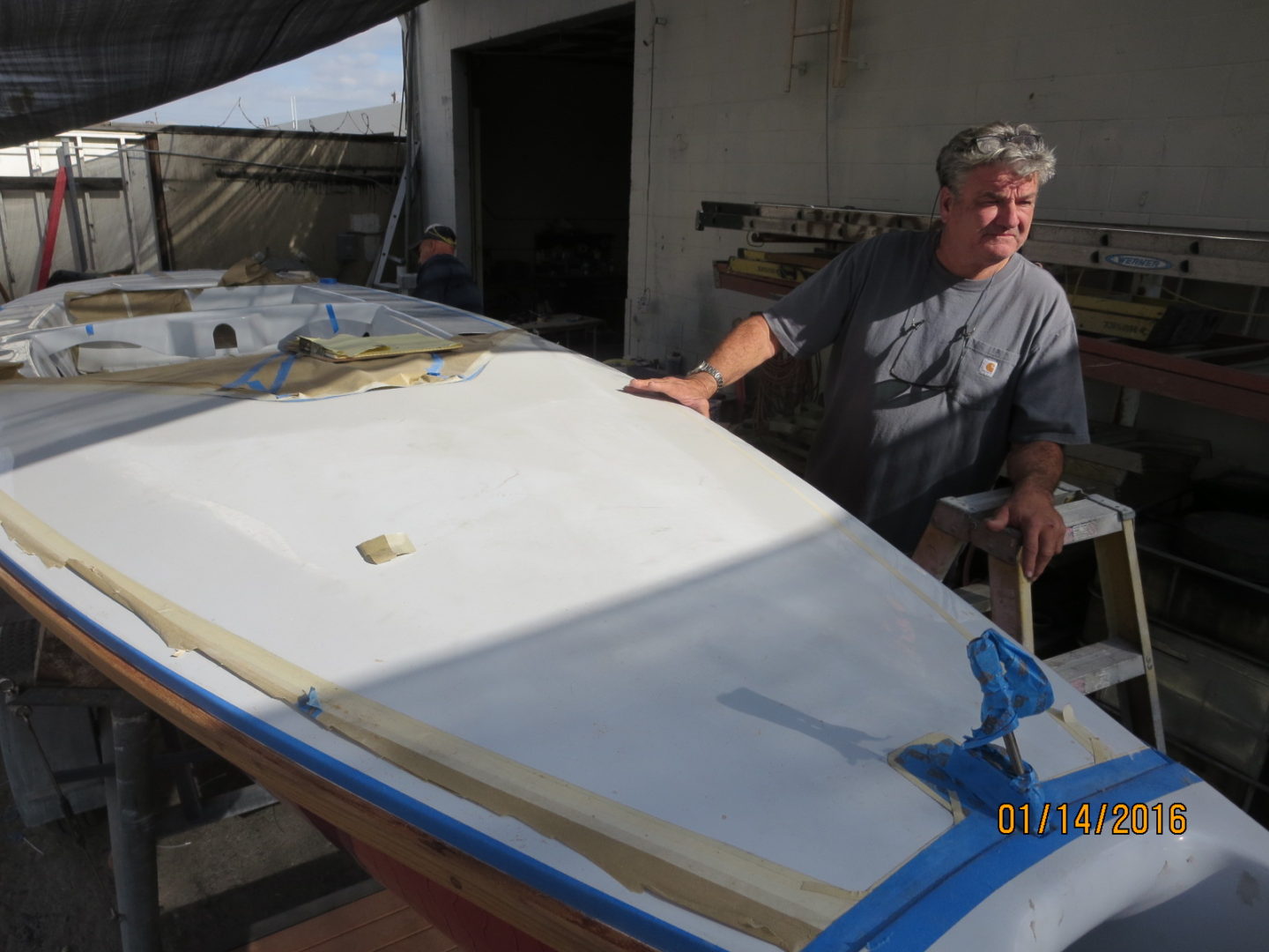 A man standing next to a boat in the sun.