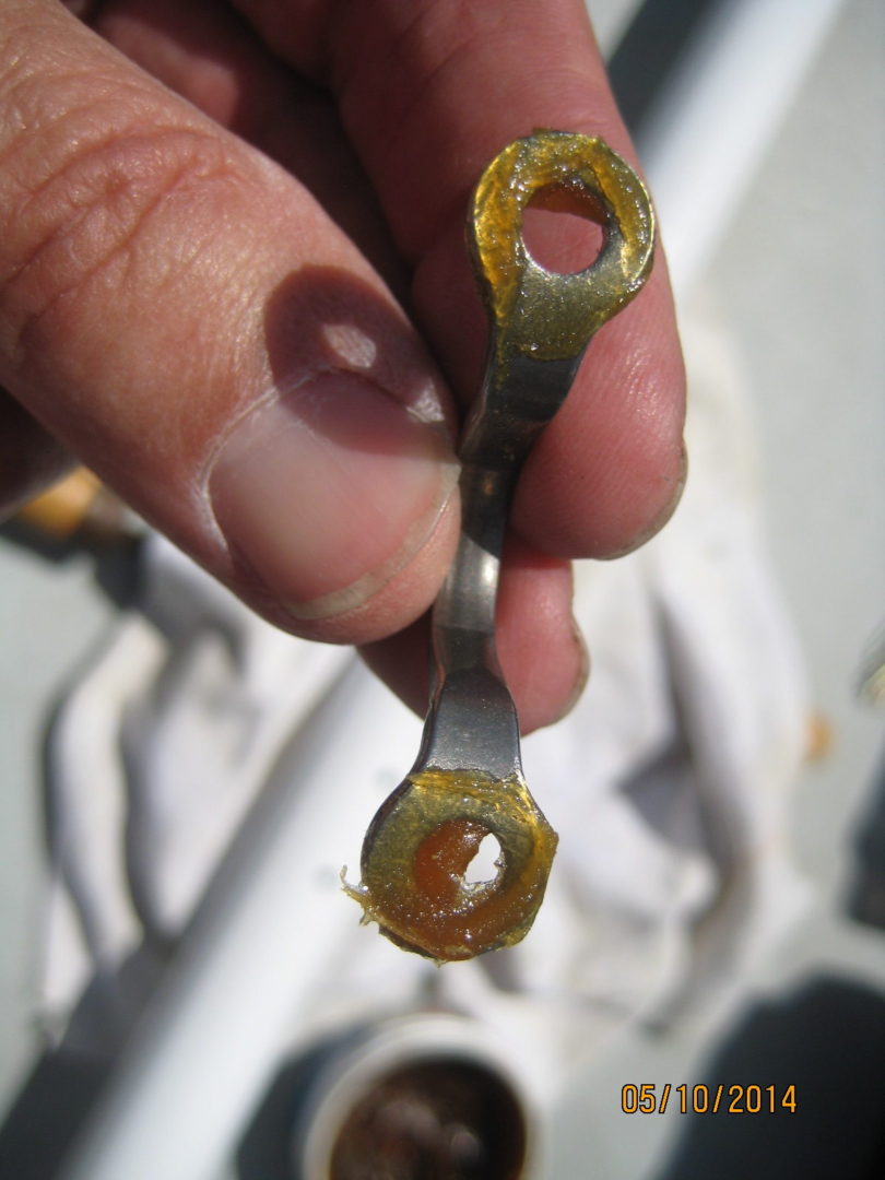 A person holding an open wrench with a piece of wax.