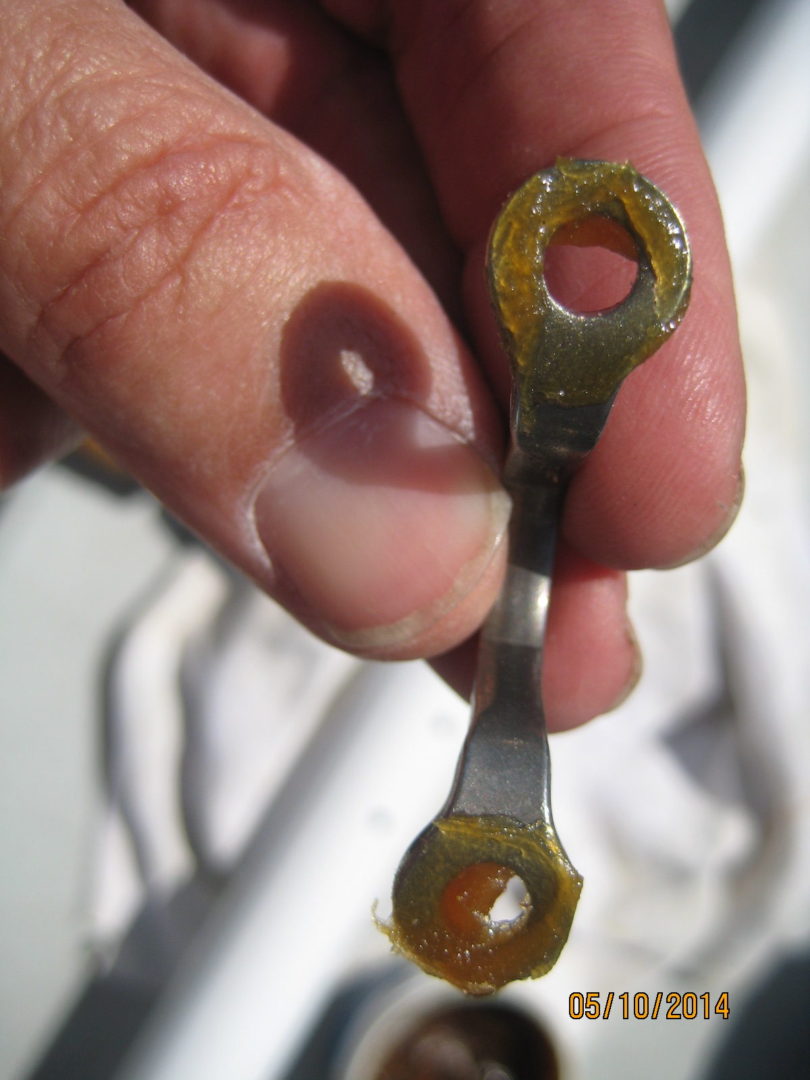 A person holding an open wrench with rust on it.