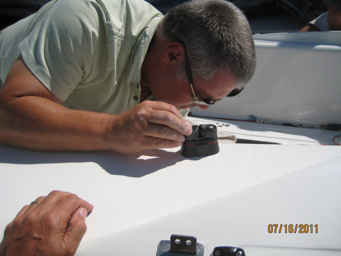 A man is looking at the camera while sitting on top of a boat.