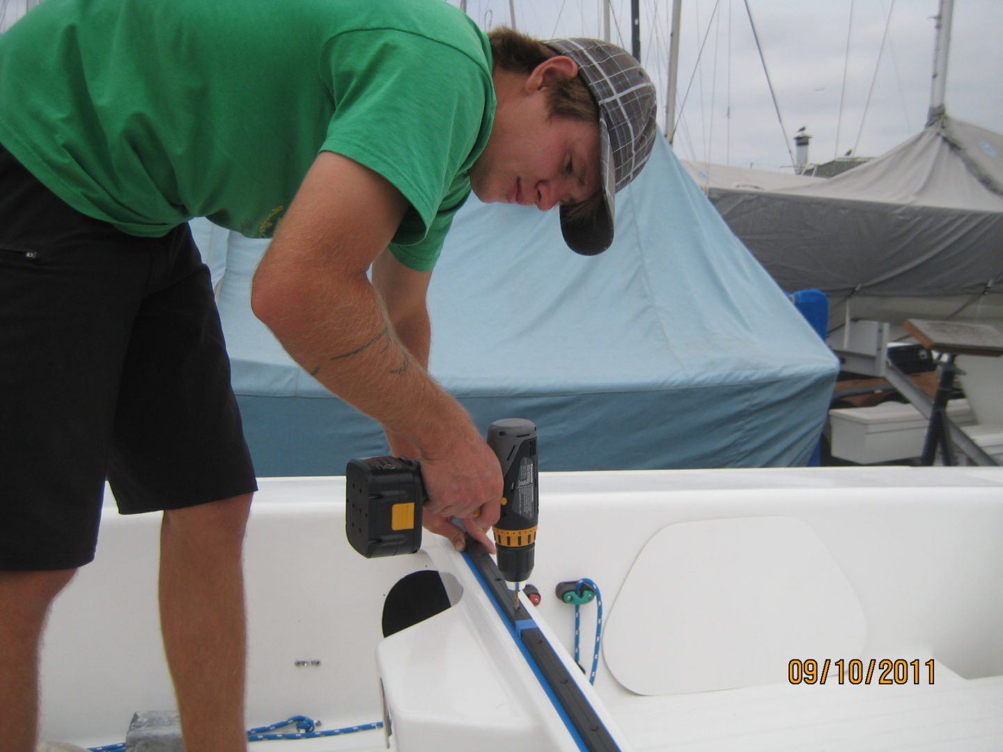 A man in green shirt holding up a blue pole.