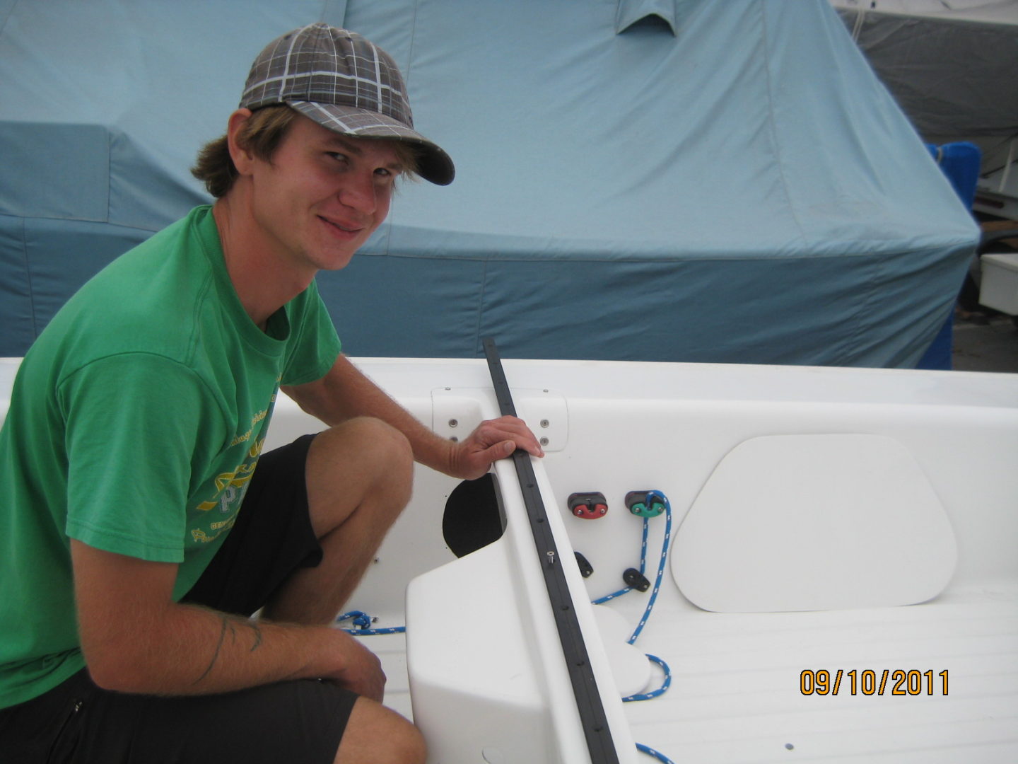 A man in green shirt and hat on boat.