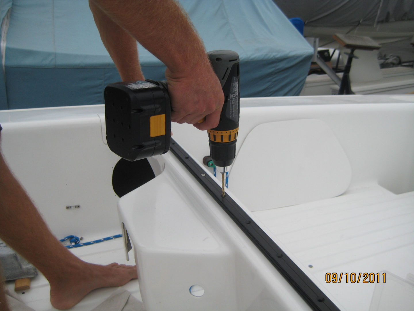 A man using a drill to install the boat 's side rails.