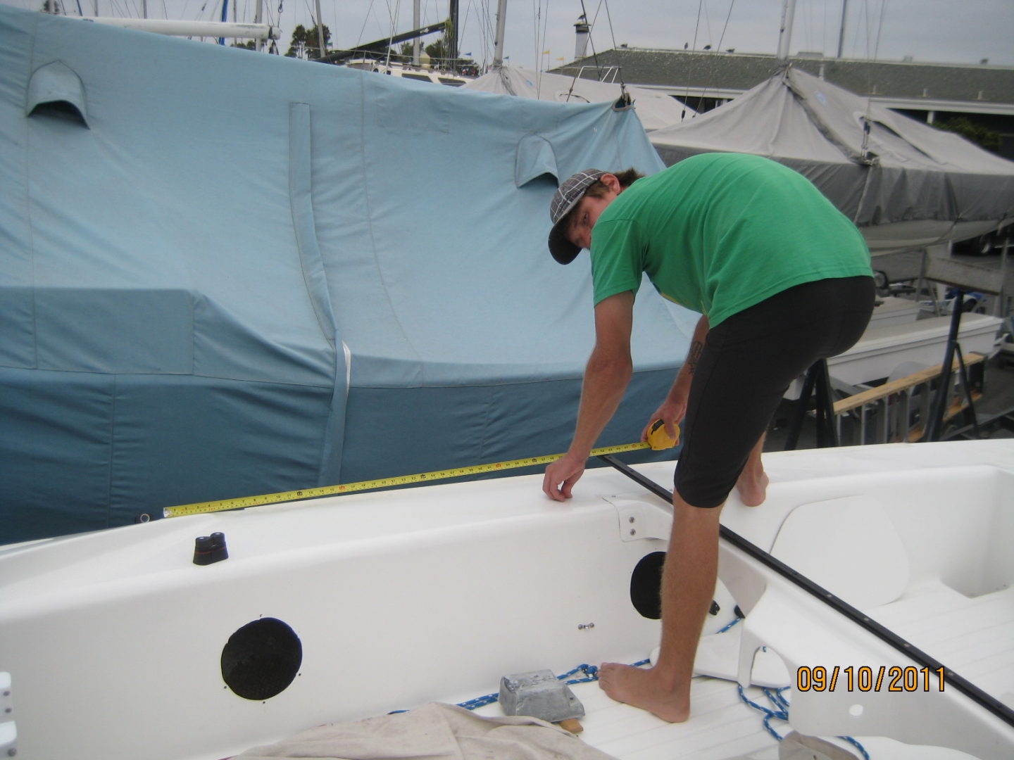 A man in green shirt standing on top of boat.