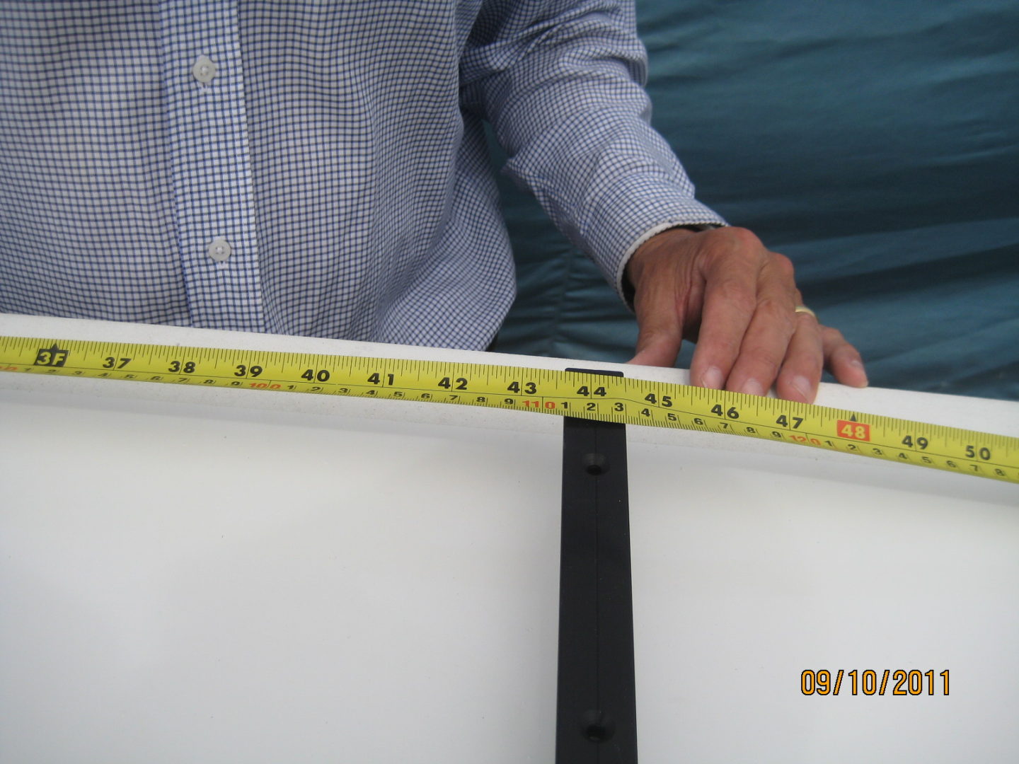 A man measuring the length of a surfboard.