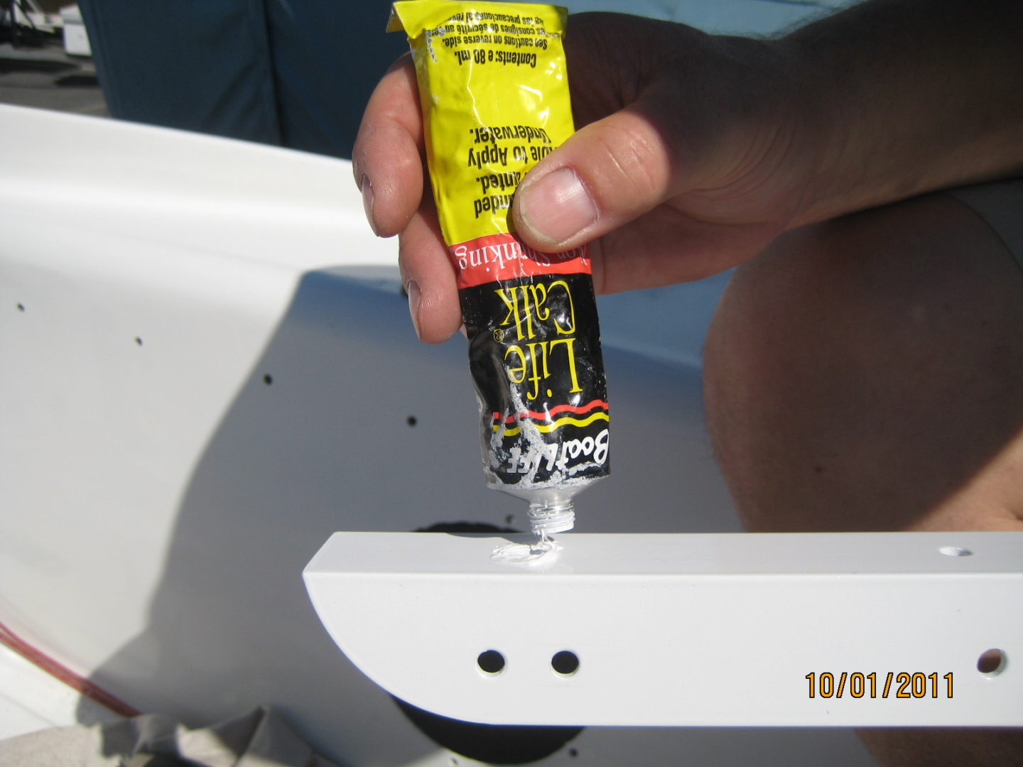 A person holding a tube of glue on top of a white table.