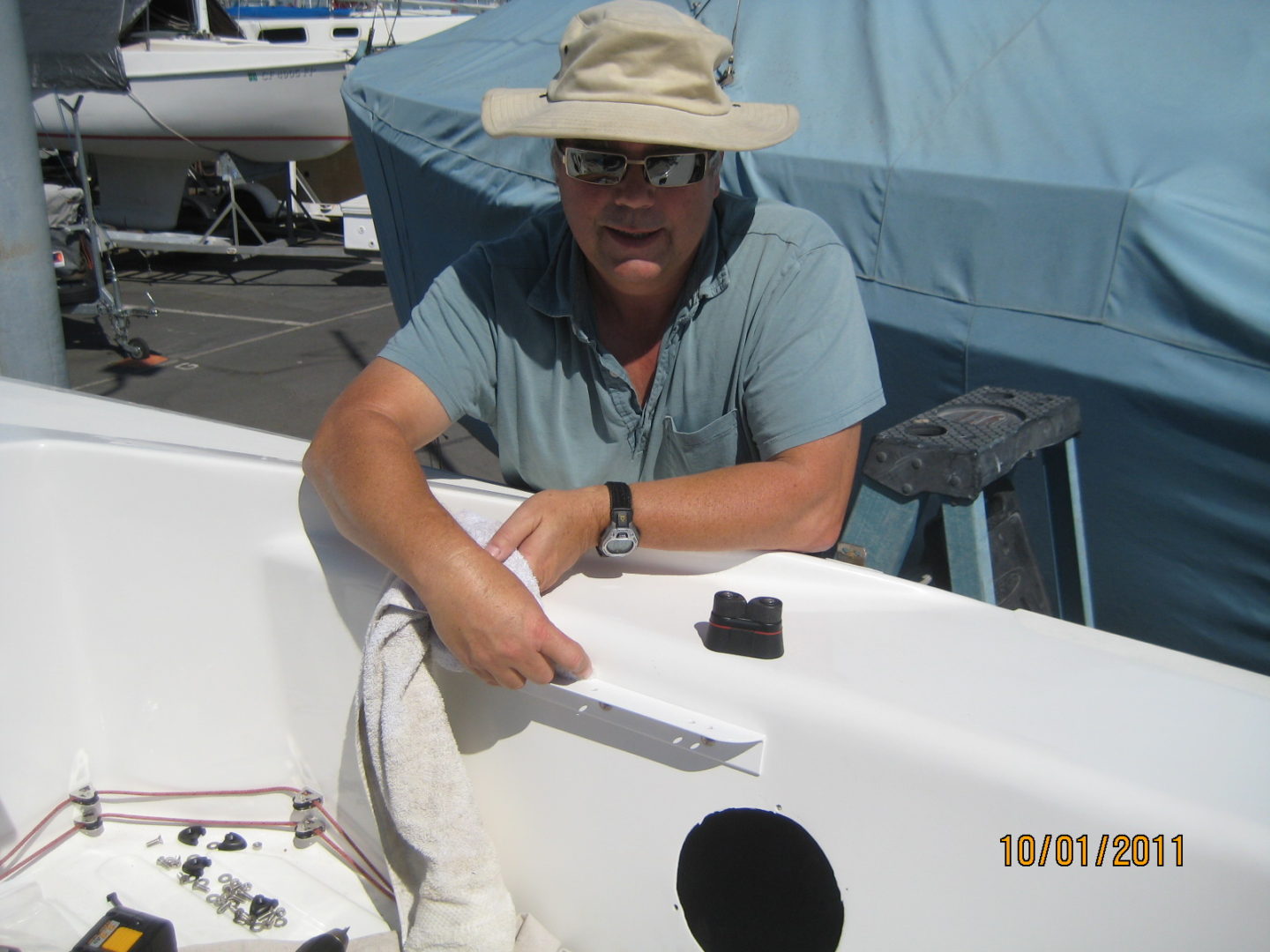 A man in a hat is sitting on the side of a boat.