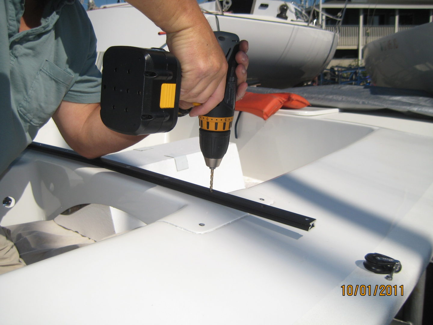 A person using a drill to install the top of a boat.