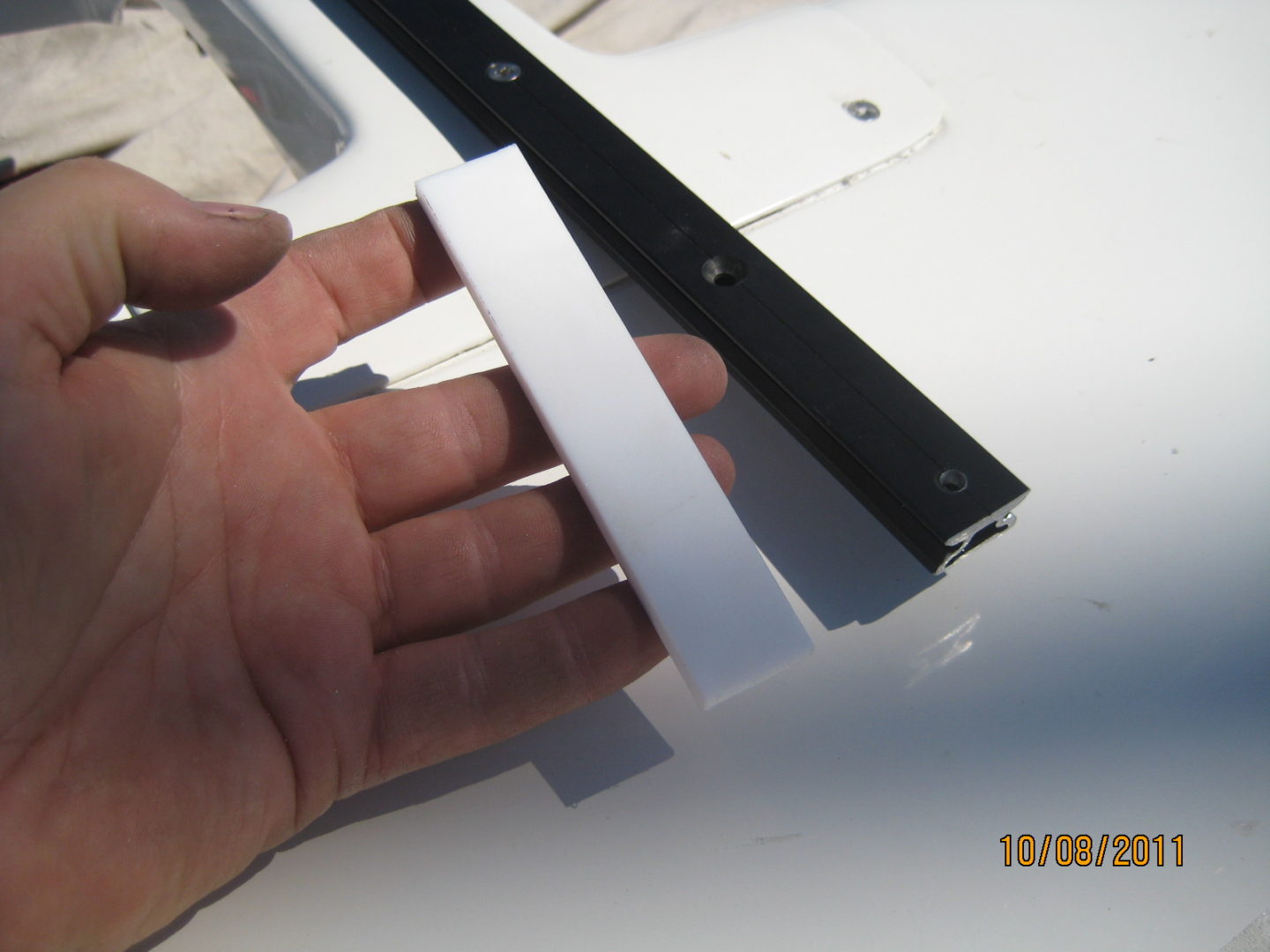 A hand holding two strips of paper with one strip cut out.