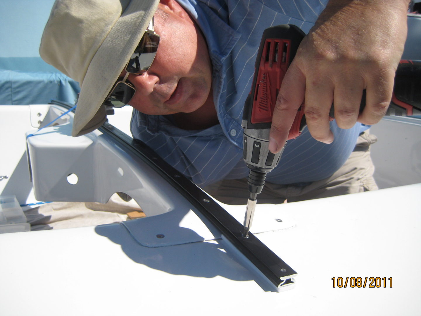 A man using a drill to cut the metal.