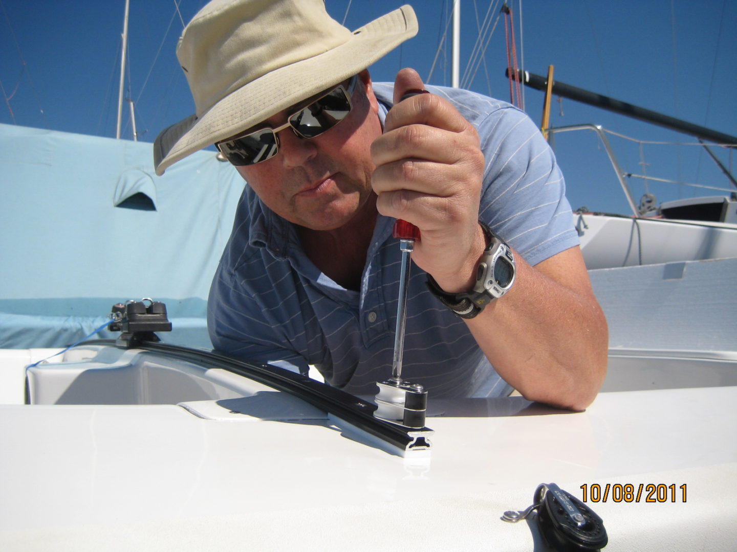 A man in a hat and sunglasses on a boat.